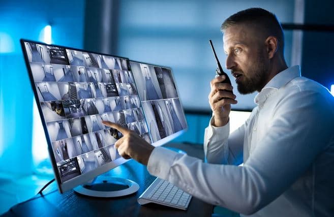 Agent de sécurité devant écrans de surveillance